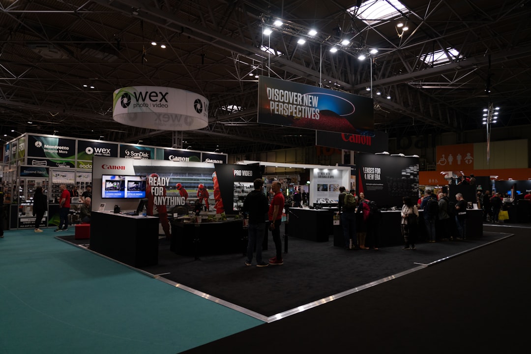 a-group-of-people-standing-around-a-trade-show-jsnivrdhdtc